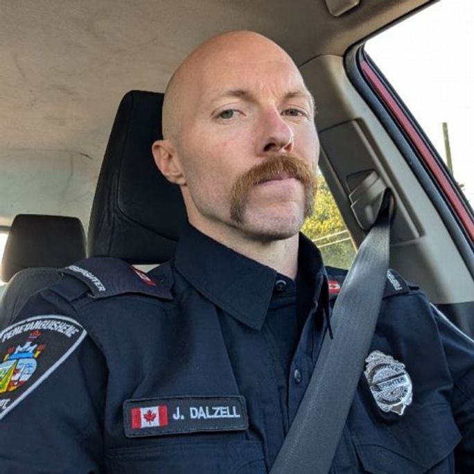 Portrait photo of a firefighter with an astoundingly handsome moustache, looking to camera.