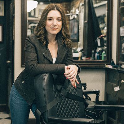Photo of Movember supporter Lauren Kaufman posing for the camera on a barber chair.