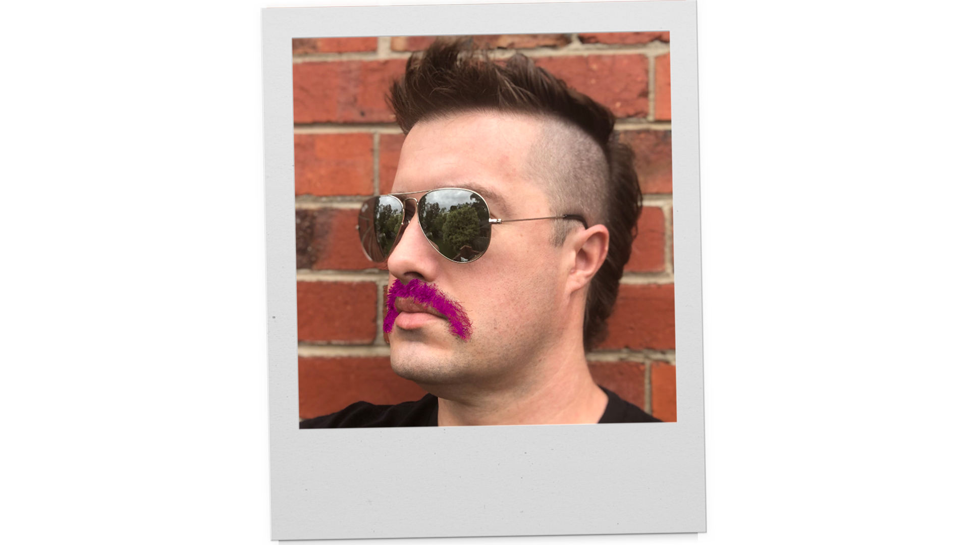 A polaroid photo of a man with a mohawk and pink moustache.