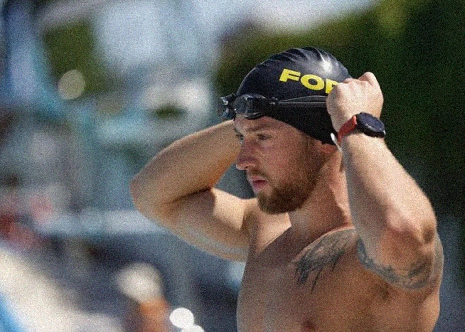 Man adjusts swimming cap to prepare for a long-distance swim.