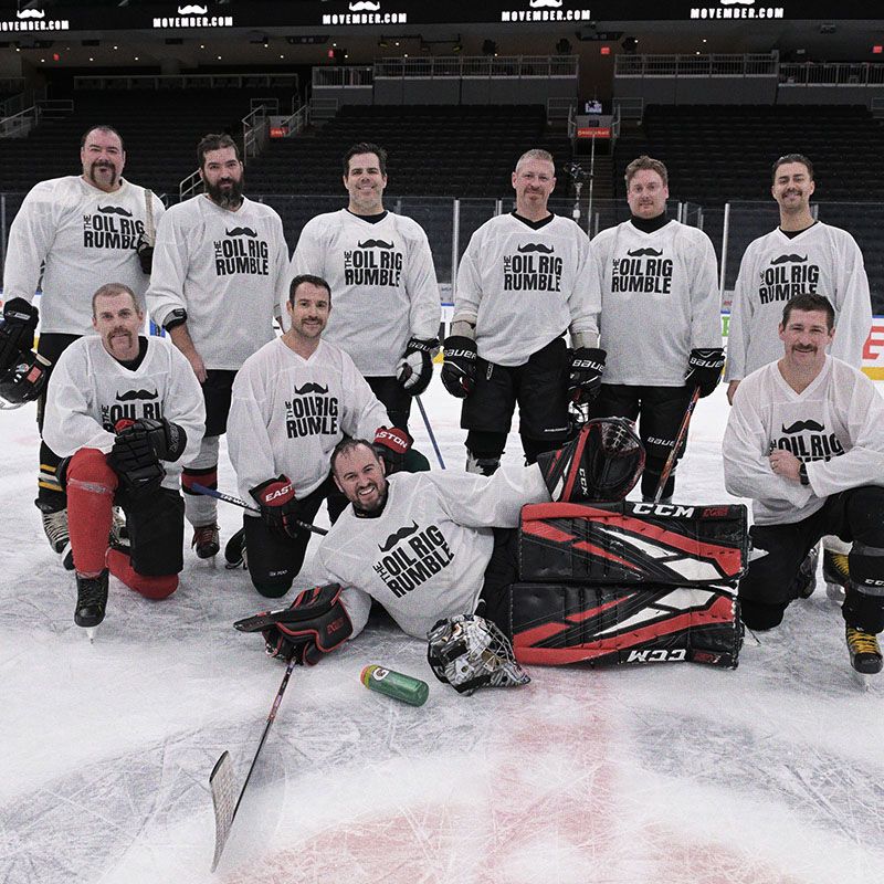 Photo of amateur ice hockey team, wearing Movember-branded shorts, posing on ice.