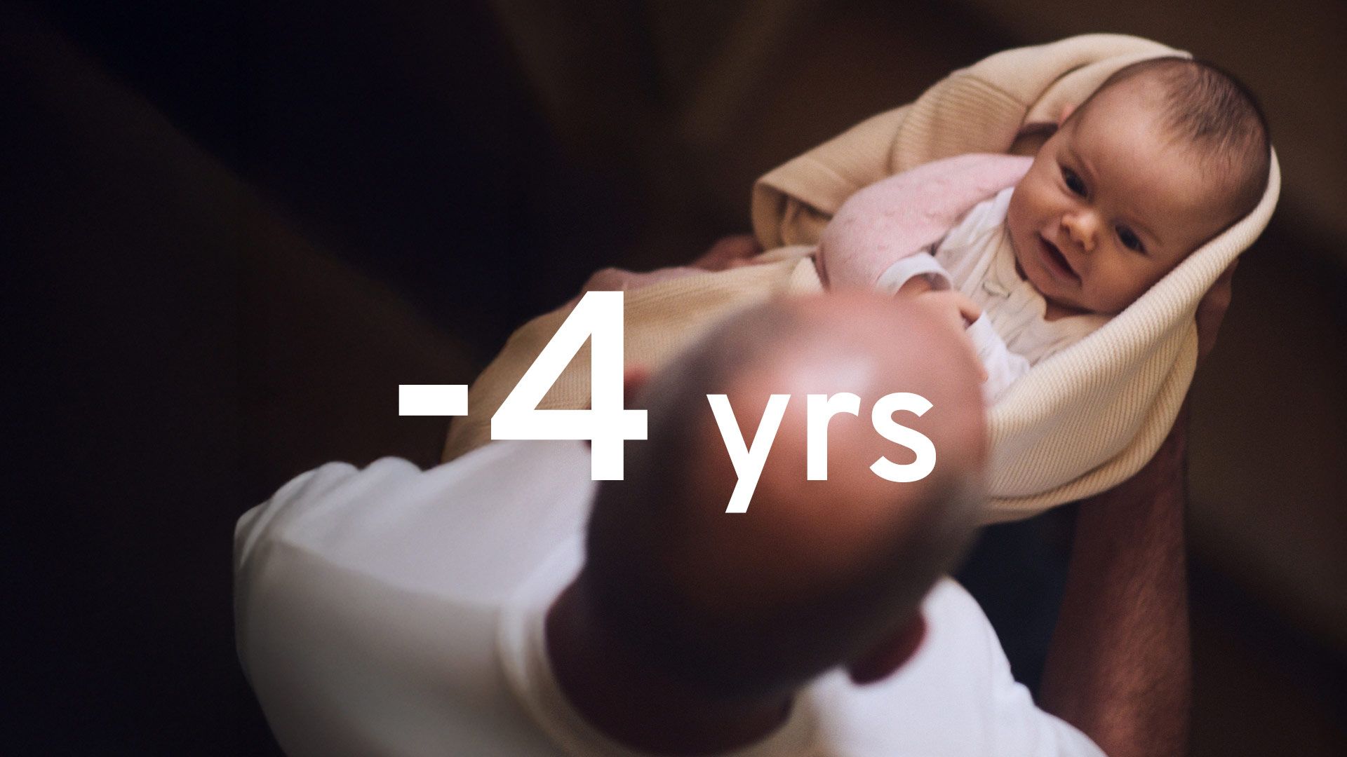 Dramatic image showing an infant, lovingly held by an elderly male relative. The words 4 year are superimposed in large white text.