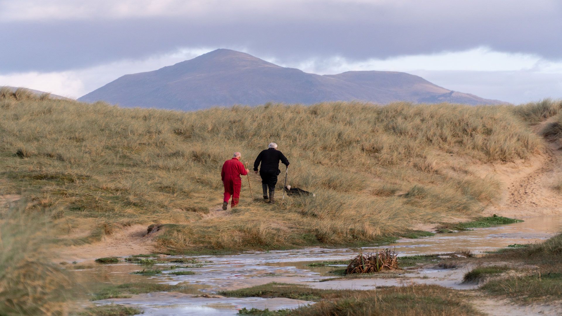 Wide shot of two people hiking through gloriously rugged Scottish wilderness.