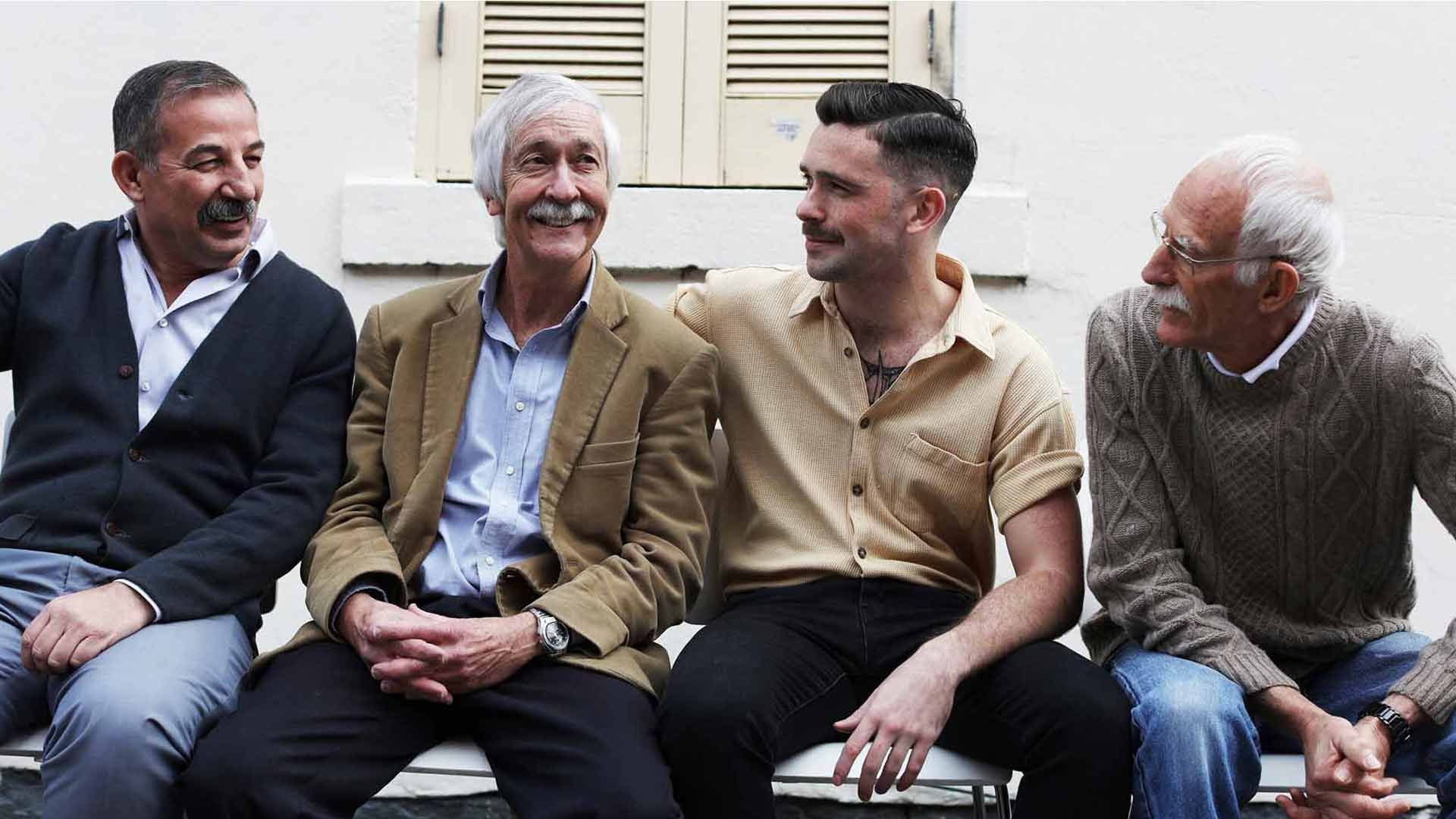 A candid photo of a group of men from different generations sitting alongside one another.