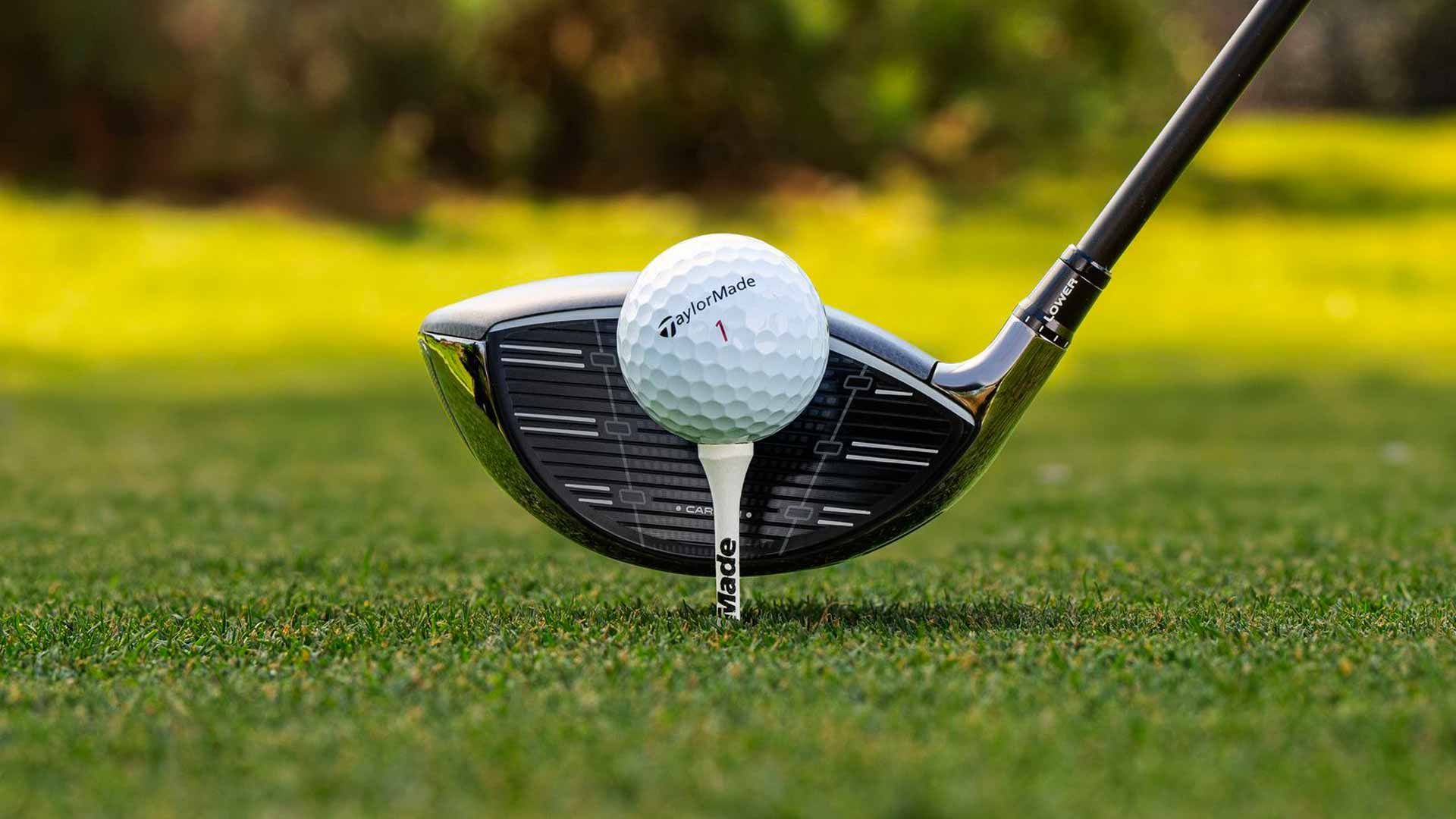 Close photo of a TaylorMade golf club about to strike a golf ball on a tee.