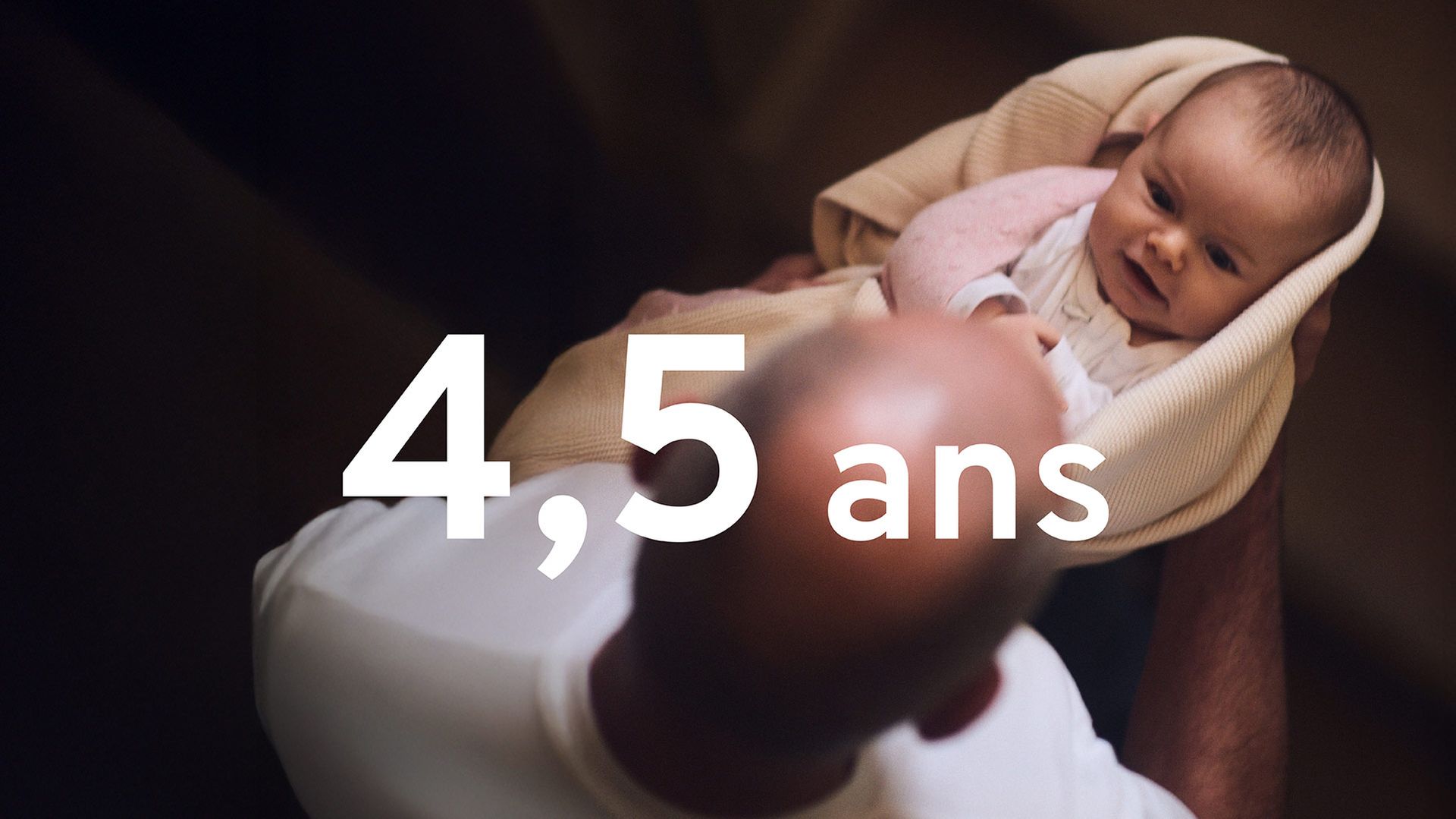 Photo of an infant, lovingly held by an elderly male relative. The French words 4,5 ans are superimposed.