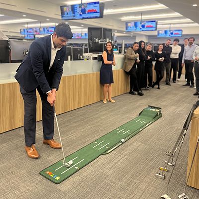 Photo of BMO corporation personnel having a jovial in-office putting contest.