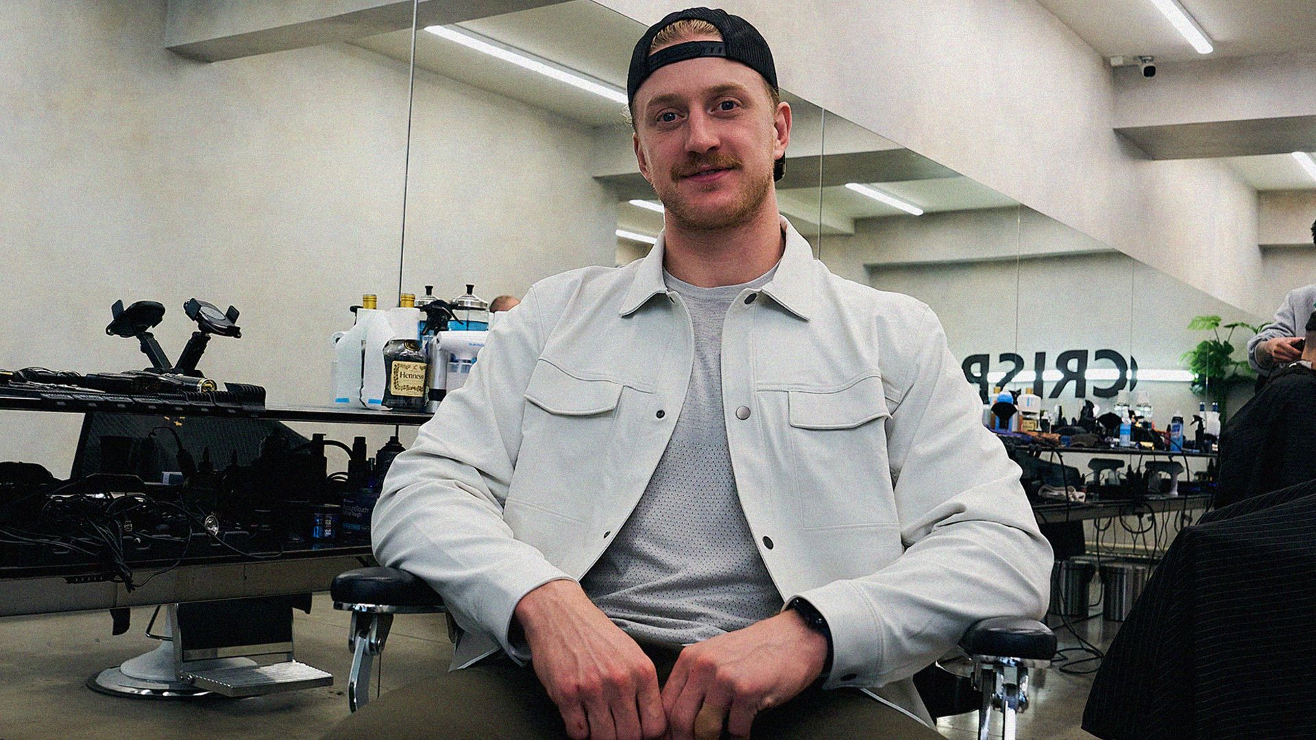 NHL hockey player Michael Pezzetta sits in a barbershop in Montreal, he's got a backwards cap on, and an epic moustache