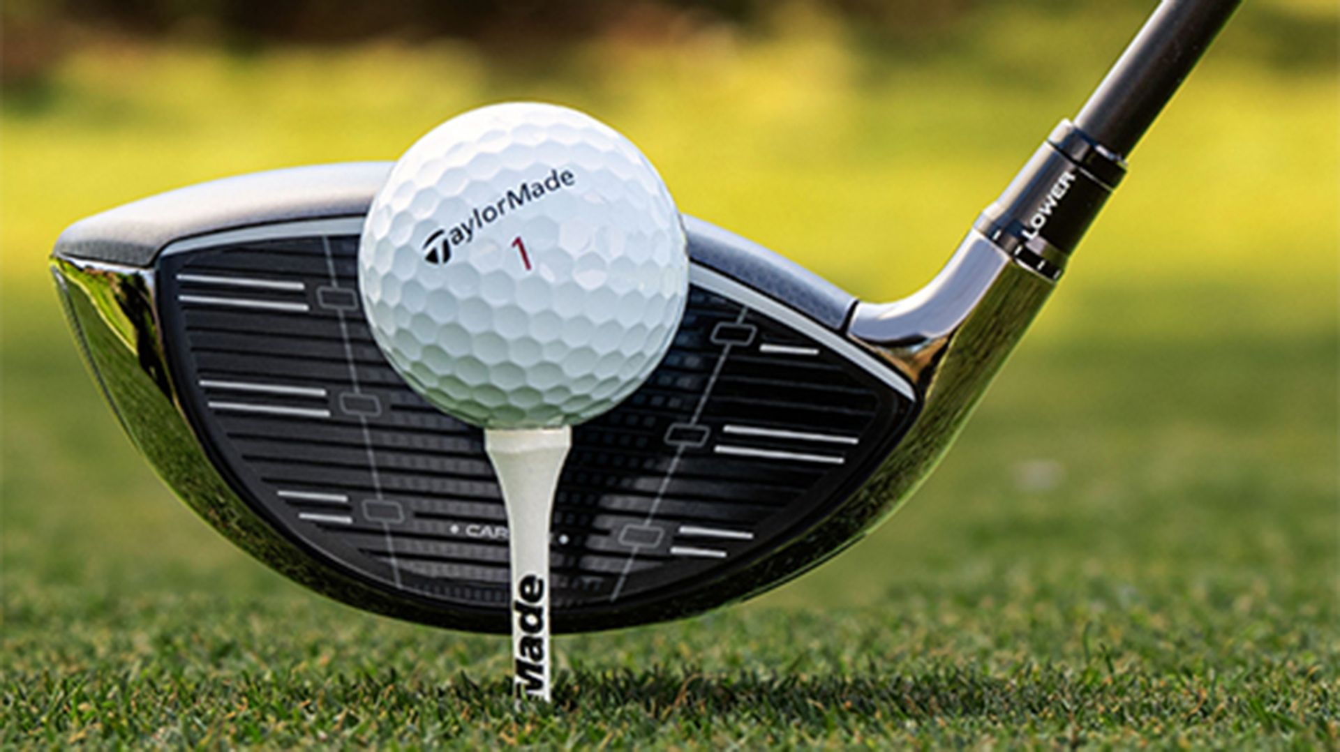 Close photo of a TaylorMade golf club about to strike a golf ball on a tee.