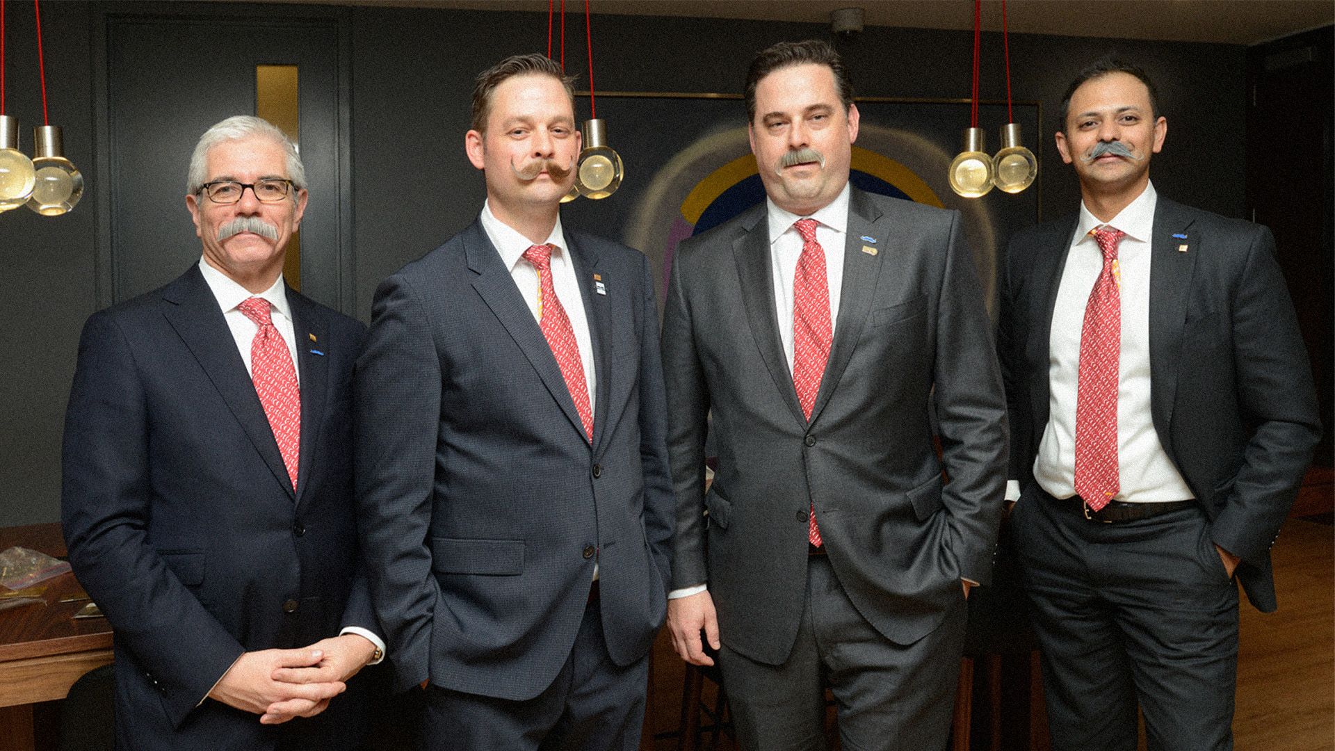 A group of people posing together on a rooftop for Movember.