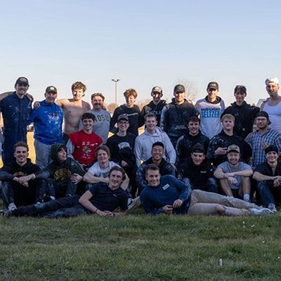 Photo of a college fraternity, posing on a playing field.