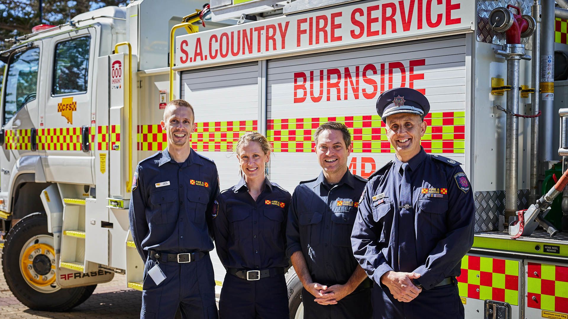 Fire service members stand together in front of fire truck