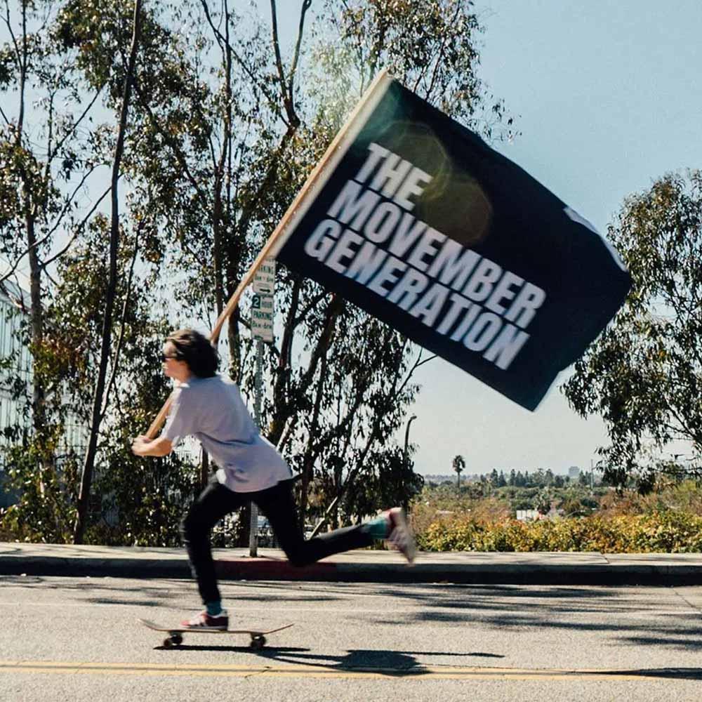 Man on skateboard, waving Movember flag.