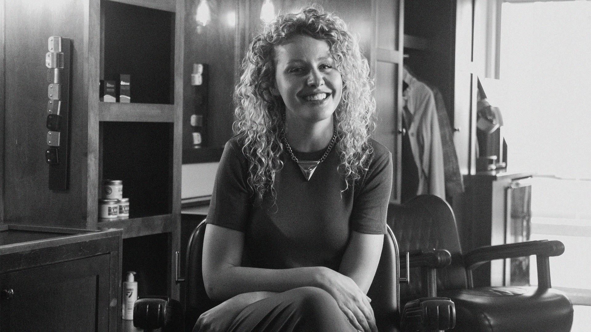 A black and white photo of a woman sitting in a barber's chair