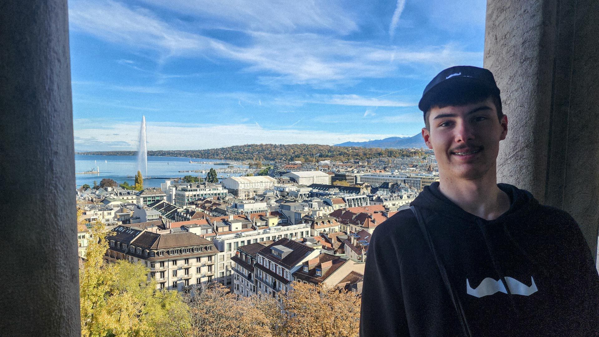 Young man at lookout with European city below with lake in background