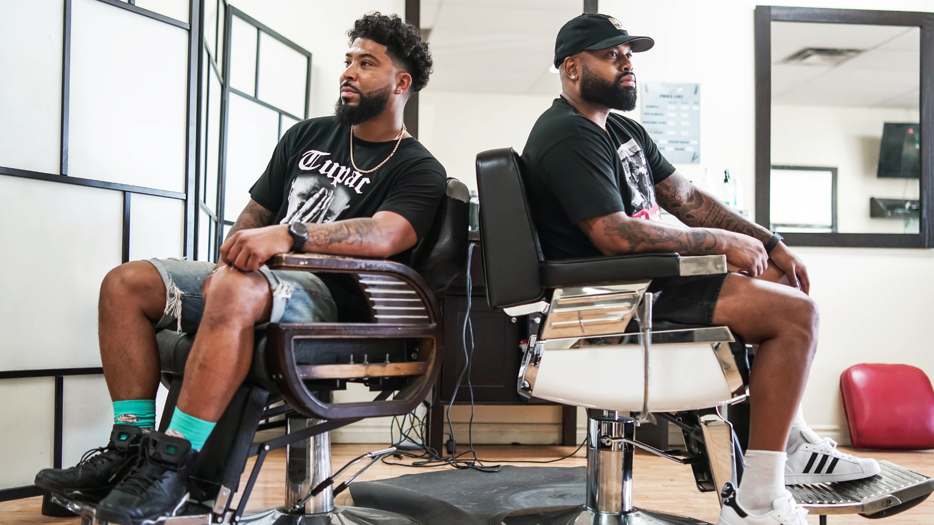 Two Black men sitting in chairs in a barbershop