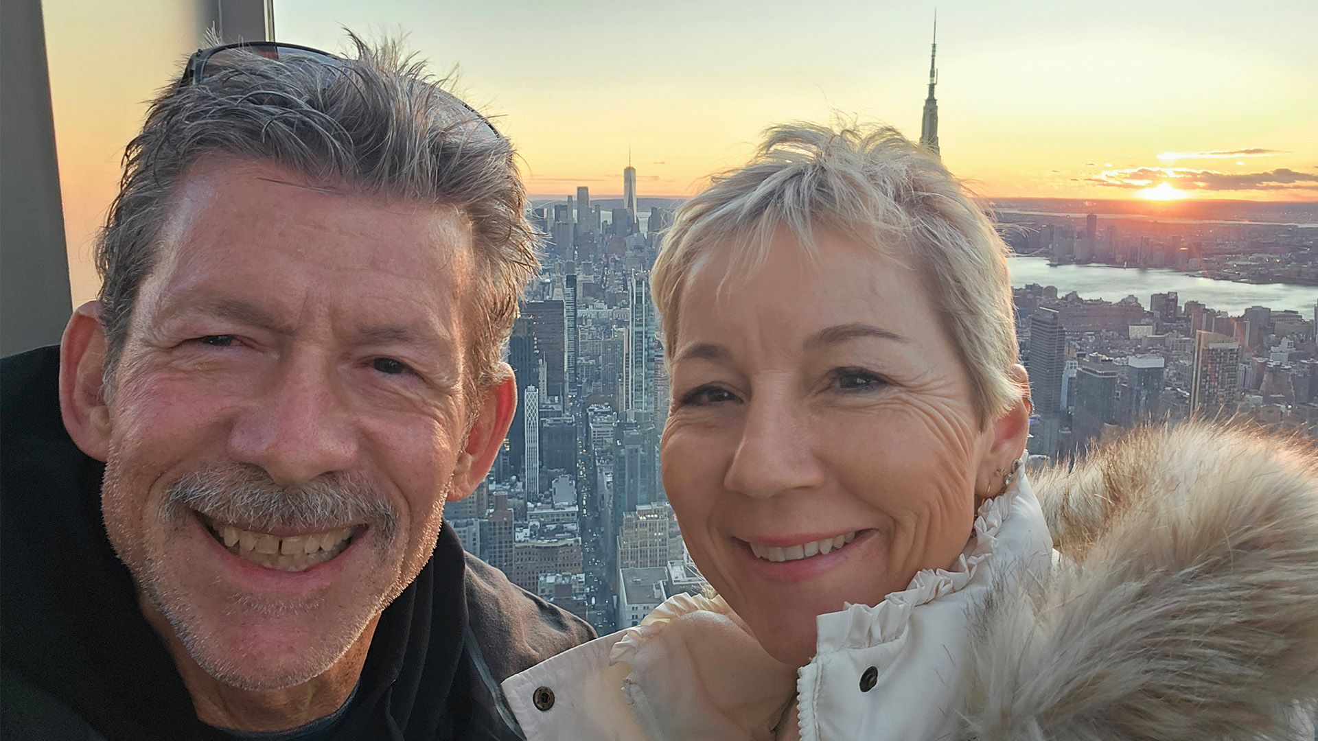 Mark and his wife in front of a city landscape