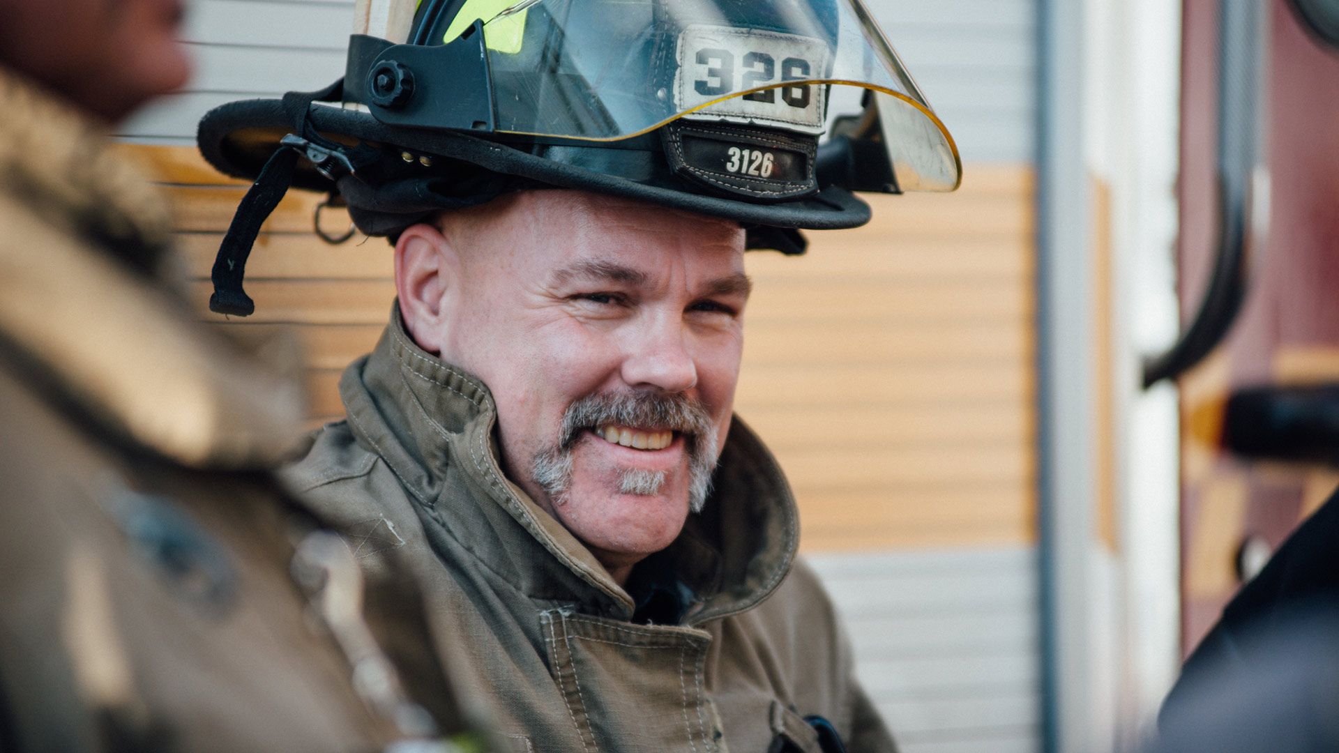 An image of a firefighter with an epic moustache smiling