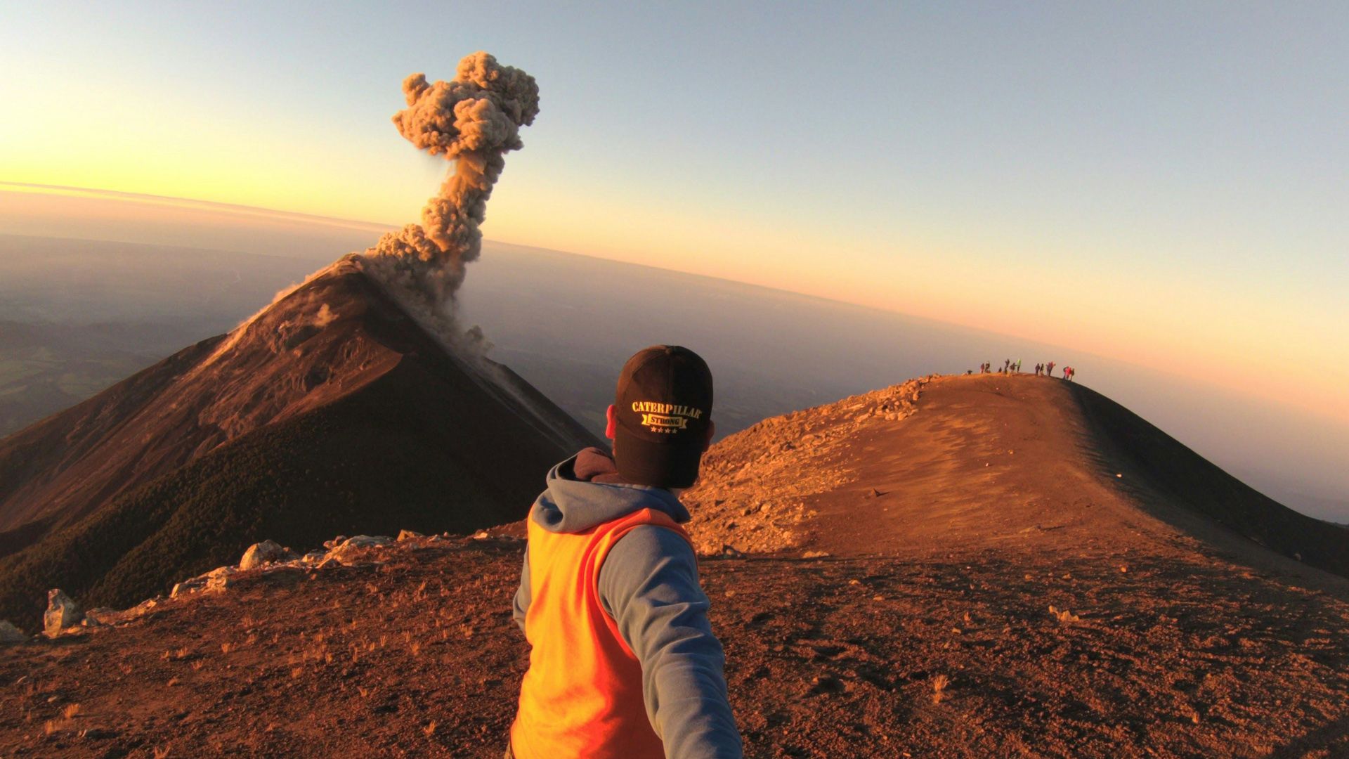 Hiker watching Fuego Volcano erupt in the distance