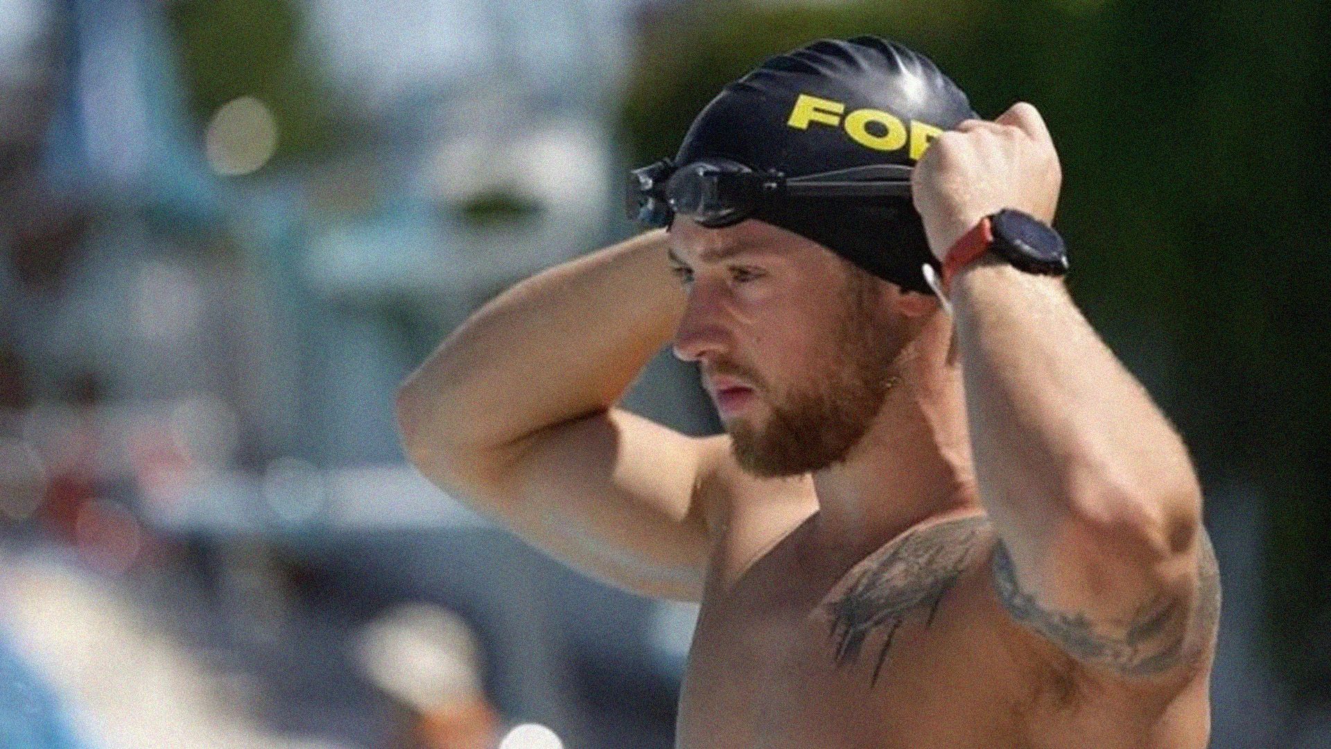 Man adjusts swimming cap to prepare for a long-distance swim.