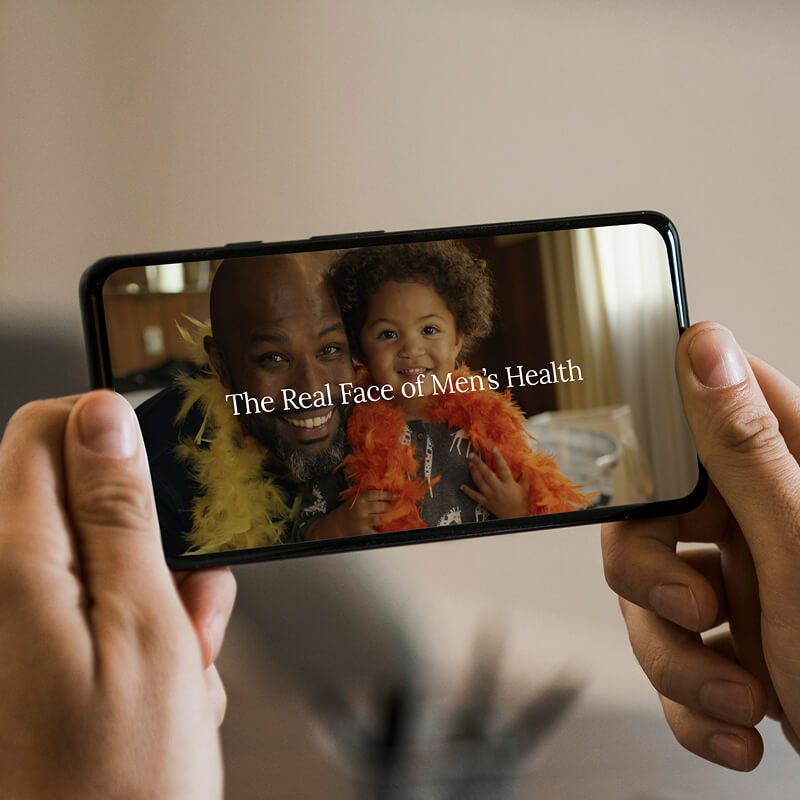Photo of a phone, playing a video about the Real Face of Men's Health.