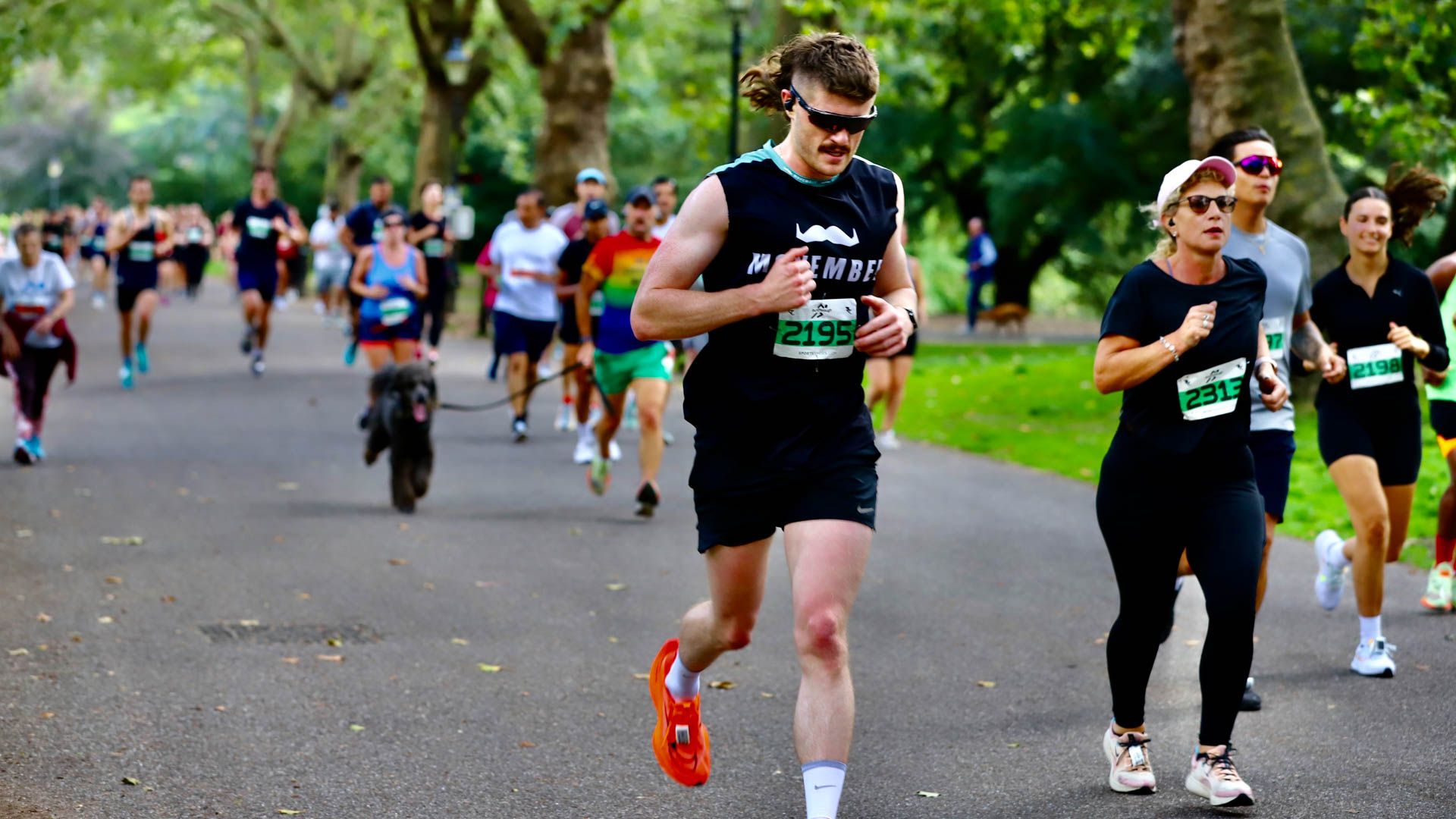 Man runs in park in Movember t-shirt with other runners around at event